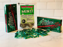Load image into Gallery viewer, Andes mint products including boxes and packaging on a marble surface with a white tiled wall background. Package of Sassy Balls Mint protein balls sitting in the middle.